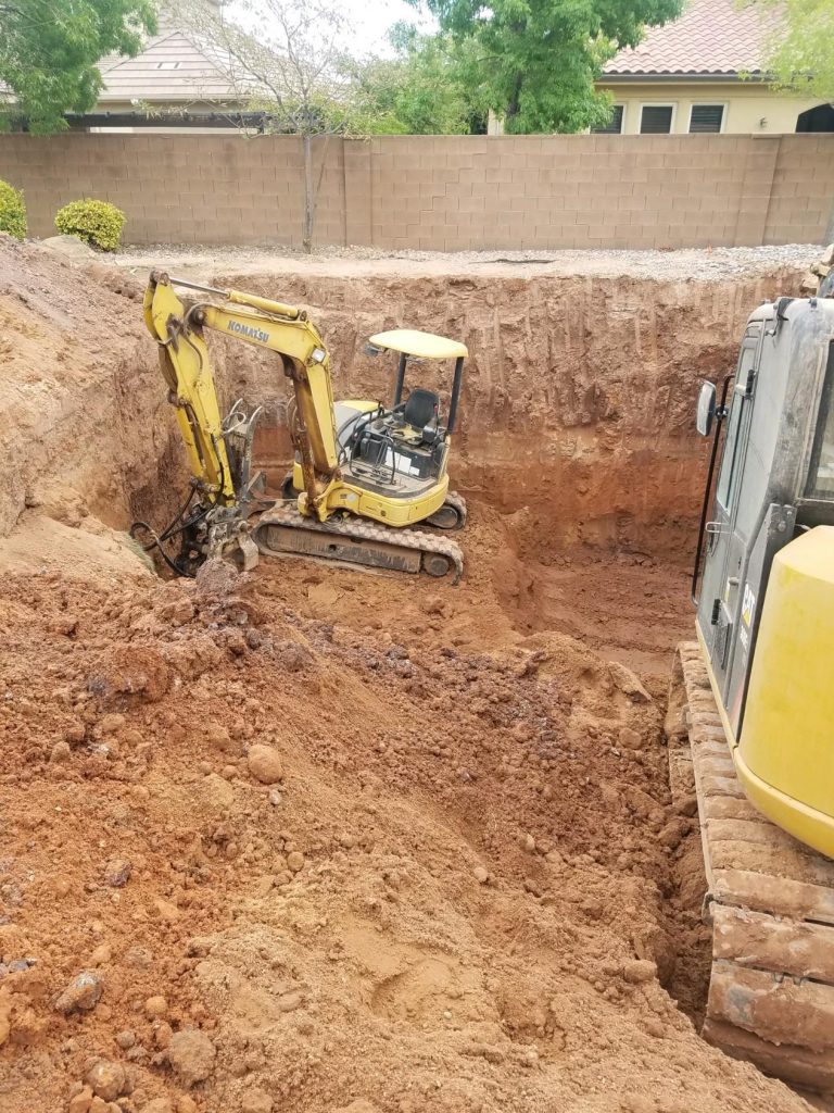 Mini excavator digging out inground swimming pool.
