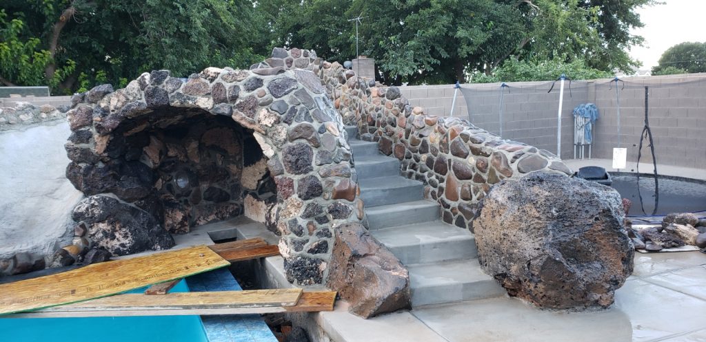 Outdoor water feature with stairs and slide over top of a cave using natural stone in Hurricane Utah.